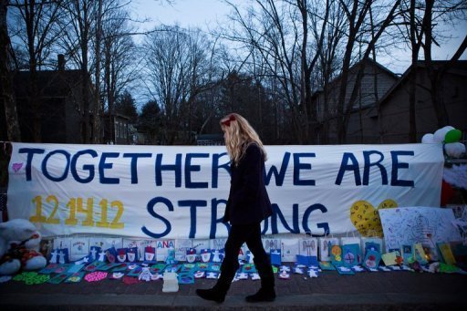 Mulher passa em frente a memorial criado em homenagem às vítimas da escola Sandy Hook