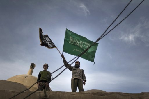 Membros da brigada rebelde Hamzah com bandeiras islamitas em cima de mesquita em Deir Ezzor