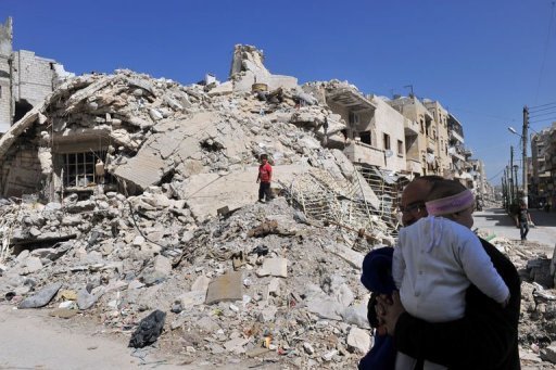 Família síria examina destroços em Maarat al-Numan, Síria, em 20 de março de 2013