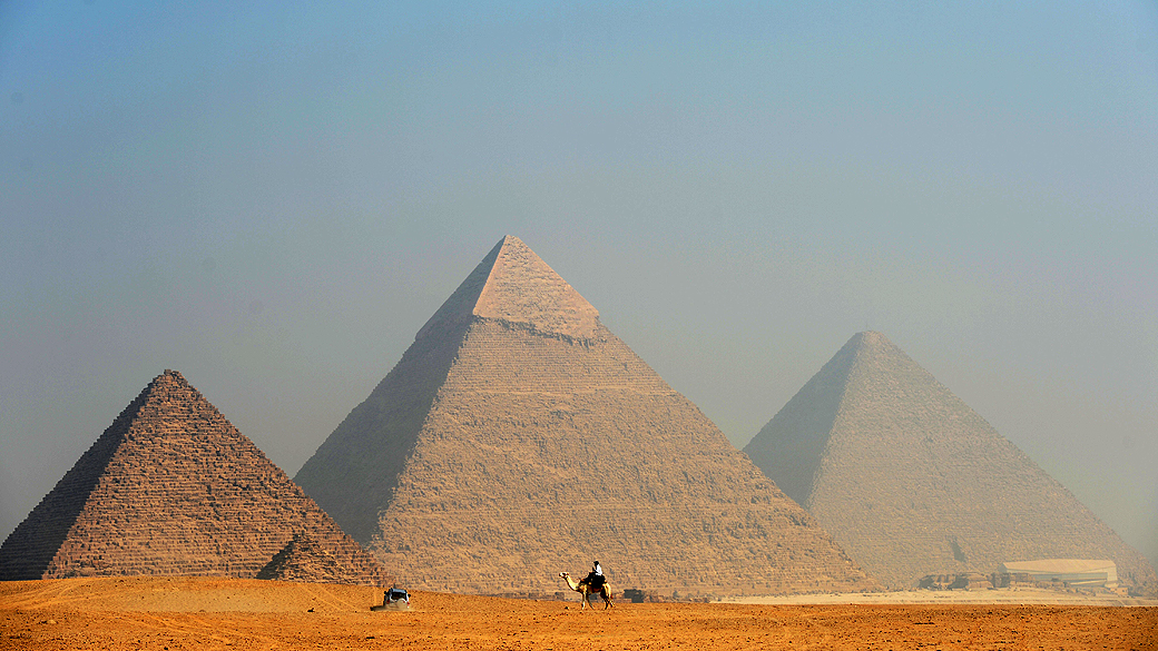 Policial faz patrulha sobre um camelo em frente às pirâmides de Giza, no Egito