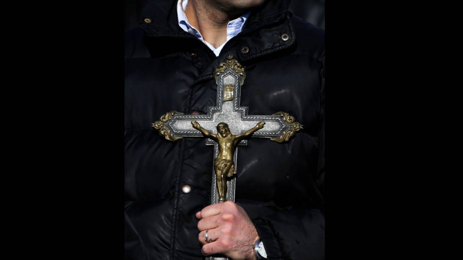 Fiel Segura crucifixo enquanto aguarda última audiência geral do Papa Bento XVI, no Vaticano