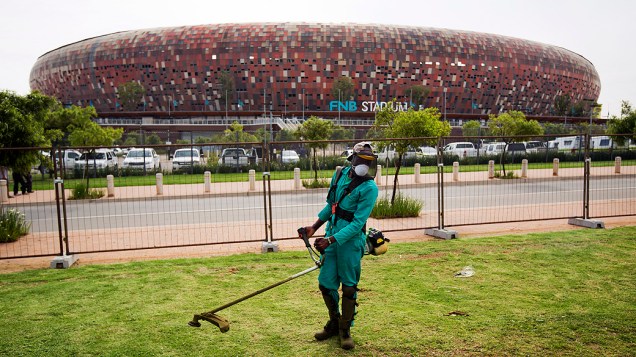 Operário apara a grama em frente ao FNB Stadium, conhecido como Soccer City que receberá evento de despedida de Mandela