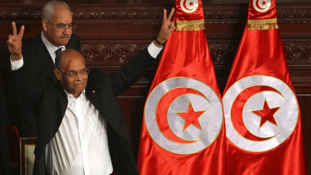 O presidente da Tunísia, Moncef Marzouki, comemora depois de assinar a nova Constituição do país