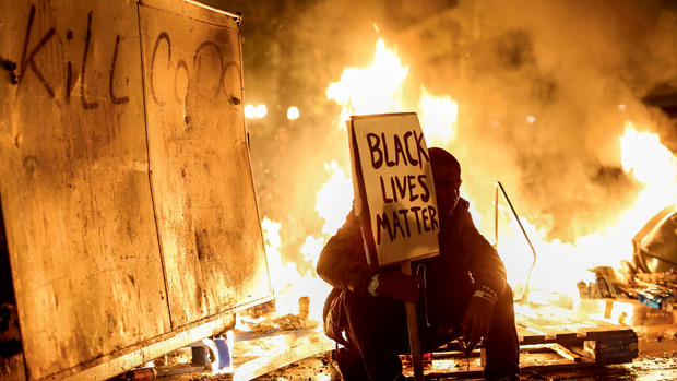 DOIS PESOS - Protesto na Califórnia, na semana passada: a pichação no canto superior esquerdo da foto pede a morte dos policiais, enquanto o cartaz diz que a vida dos negros importa