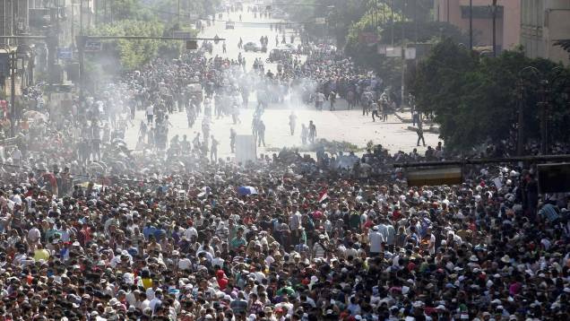 Manifestantes correm após bomba de gás lacrimogêneo ser disparada contra protesto no Cairo