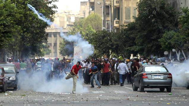 Manifestante arremessa bomba de gás lacrimogêneo disparada contra marcha pró-Mursi, no Cairo