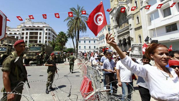 Manifestante leva bandeira da Tunísia durante protesto na capital Túnis, depois da morte do opositor Mohamed Brahmi
