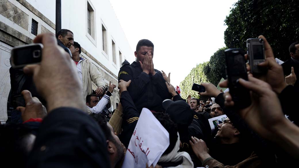 Manifestantes utilizam telefone celular durante protestos na Tunísia