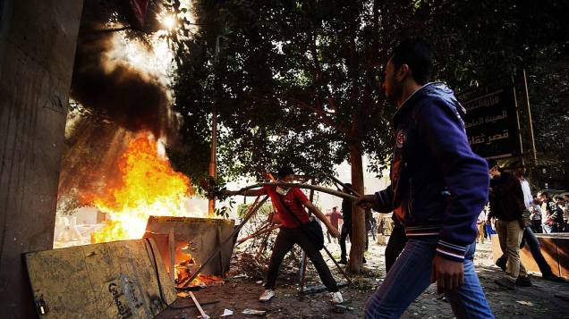 Manifestantes alimentam fogueira em confronto com a polícia durante protesto contra novas determinações do presidente do Egito, Mohamed Mursi