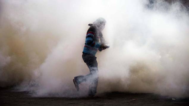 Manifestante em meio a fumaça durante confronto com policiais perto da Praça Tahrir, no Cairo, Egito