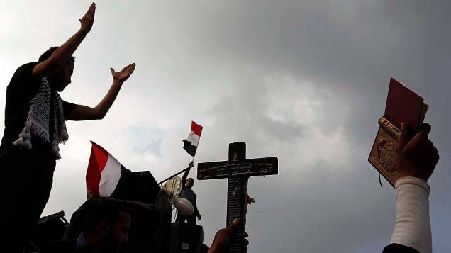 Na Praça Tahir, manifestante segura uma cruz e o livro do Corão, durante protesto contra decreto que aumenta poderes do presidente Mohamed Mursi