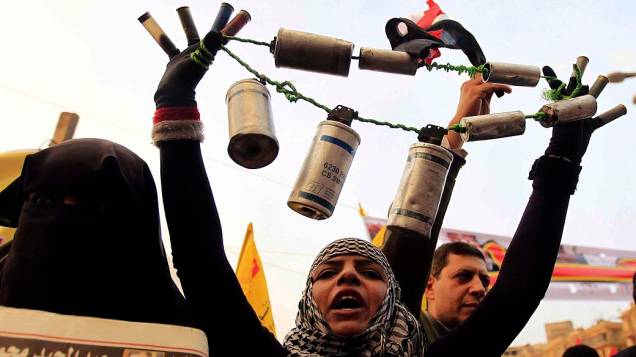 Mulher exibe latas de gás lacrimogênio e balas de borracha usadas pela polícia durante manifestação na Praça Tahrir, no Cairo