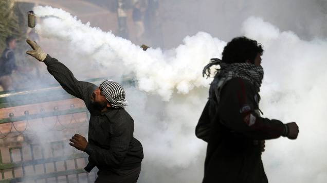 Manifestantes com bomba de gás durante confronto com policiais, na Praça Tahrir