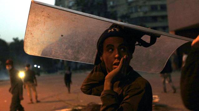 Manifestante com escudo de policial durante confronto perto da Praça Tahrir, no Cairo
