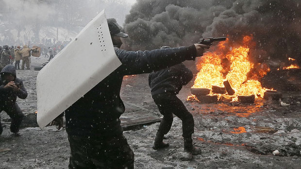 Manifestante aponta arma contra policiais, em Kiev
