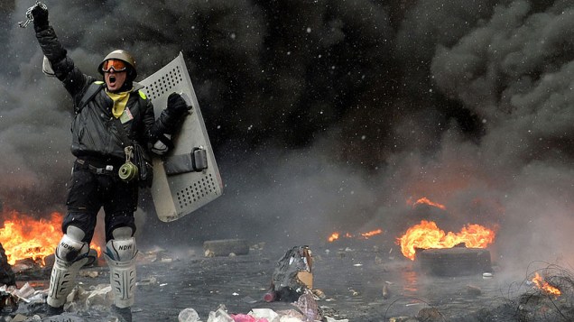 Manifestante entre pneus em chamas e detritos no centro de Kiev, na Ucrânia