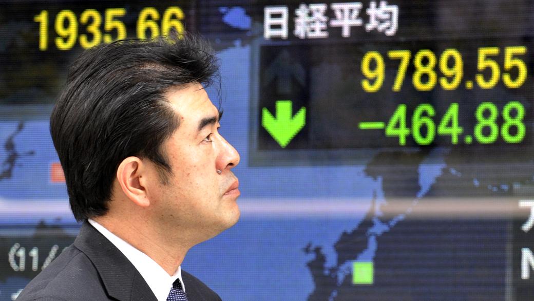 Executivo passa diante de painel com dados da Bolsa de Tóquio nesta segunda-feira, primeiro dia de pregão depois do terremoto e tsunami de sexta; as ações despencaram