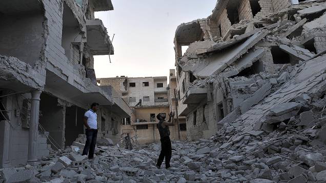 Pessoas rezam sobre as ruínas de prédio bombardeado pela Força Aérea Síria na cidade de Maaret al-Numan, no noroeste do país, região sob controle do exército rebelde