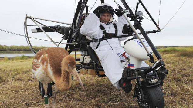 O presidente russo, Vladimir Putin, se senta em um deltaplano motorizado perto de uma cegonha no distrito de Yamalo-Nenets