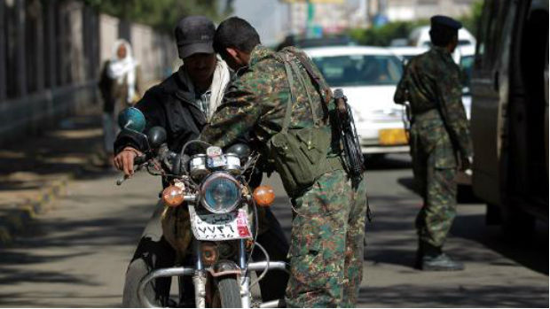 Soldado iemenita revista motociclista em posto de controle da capital Sana