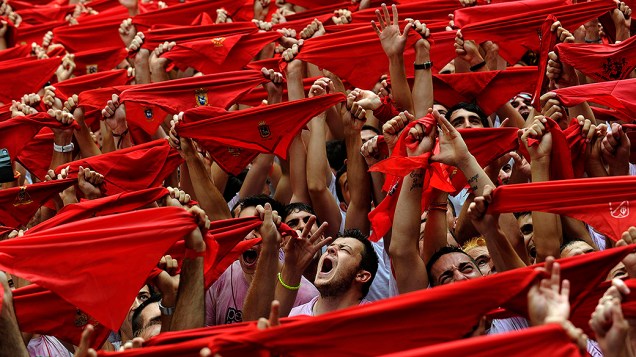 Centenas de pessoas seguram lenços vermelhos que fazem parte da tradicional vestimenta do Festival de São Firmino, que ocorre anualmente na cidade histórica de Pamplona, na Espanha, entre os dias 06 e 14 de julho