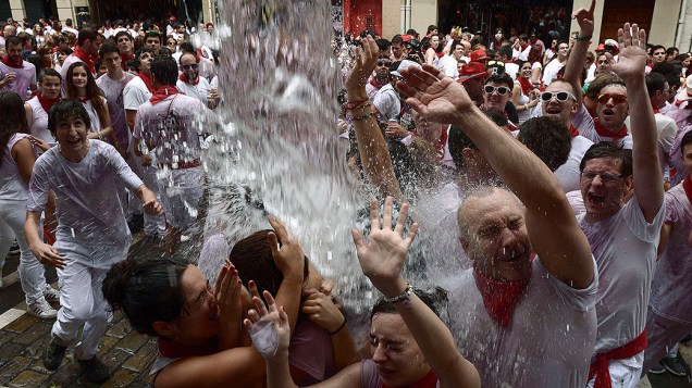 Foliões são regados por água lançada de uma varanda após o anúncio de início do Festival de São Fermino, na cidade de Pamplona, na Espanha. O tradicional evento ocorre anualmente entre os dias 6 a 14 de julho e tornou-se, ao longo do século XX, uma das festas mais famosas em todo o mundo