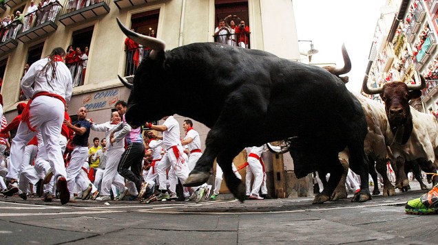 Homens participam da tradicional corrida de touros durante o festival de São Firmino em Pamplona, na Espanha