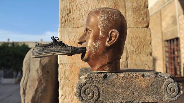 Um sapato é colado na boca de uma estátua do falecido presidente da Síria Hafez al-Assad, no museu de Maaret al-Numan