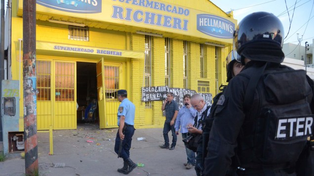 Policiais na entrada de supermercado saqueado, em Córdoba