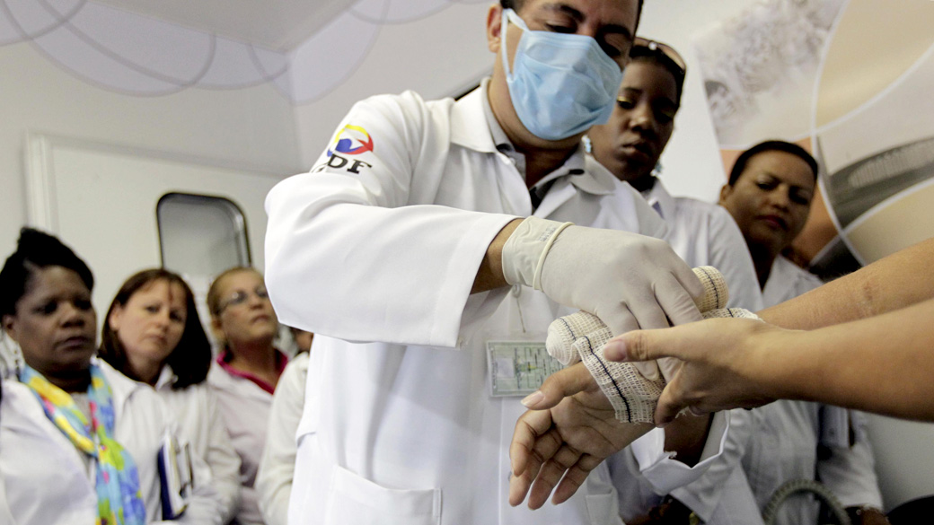 Médico estrangeiro do programa "Mais Médicos" faz um curativo em uma paciente do SUS