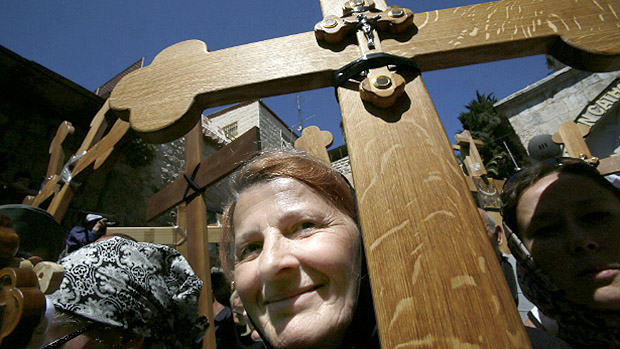 Fiel cristã carrega cruz no percurso da Via Crucis, em Jerusalém