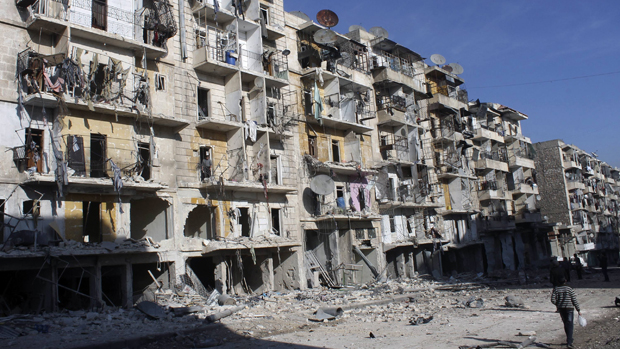 As pessoas passam por edifícios danificados em Aleppo