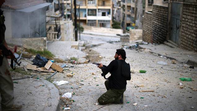 Soldado do Exército Livre da Síria dispara contra forças do regime no disputado bairro de Izza, em Aleppo, no norte do país