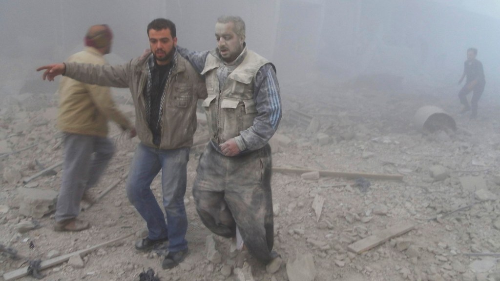 Rebeldes sírios são fotografados perto de prédios destruídos por bombardeios. Ativistas afirmam que o Exército sírio lançou mísseis no bairro de Akraba, em Damasco