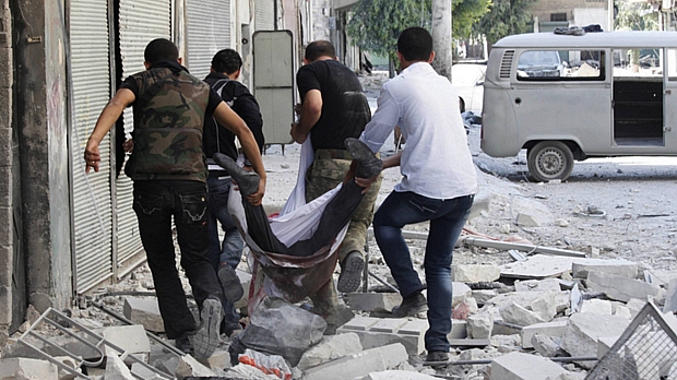Combatentes do Exército Livre Sírio carregam homem morto em combate na cidade de Alepo