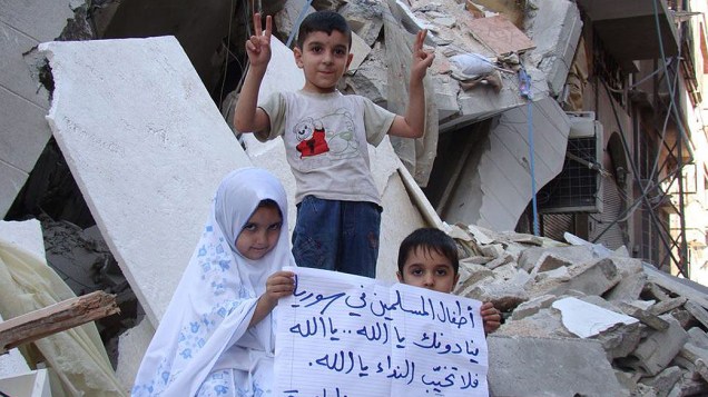 Crianças seguram cartaz: “Crianças muçulmanas estão chamando pelo nosso senhor Deus. Mas Deus não está respondendo”