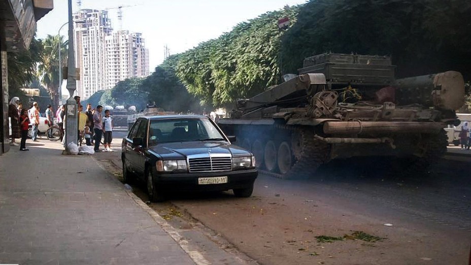 Tanques do regime sírio passam por rua da cidade de Homs