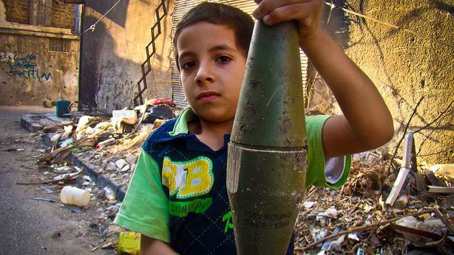 Menino sírio segura morteiro intacto e supostamente disparado por tropas governamentais