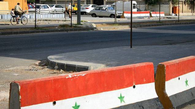 Barreiras de concreto pintados com a bandeira oficial da Síria separam distritos e mostram que estão sob controle de tropas do governo