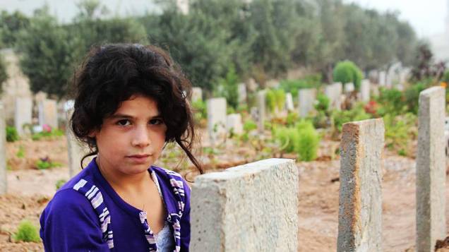 Menina síria em um dos cemitérios da cidade de Homs