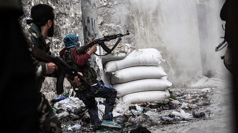 Membro do Exército Livre da Síria em busca de abrigo contra tiros de inimigos na linha de frente de Moaskar, um dos campos de batalha no bairro de Karmal Jabl, em Aleppo