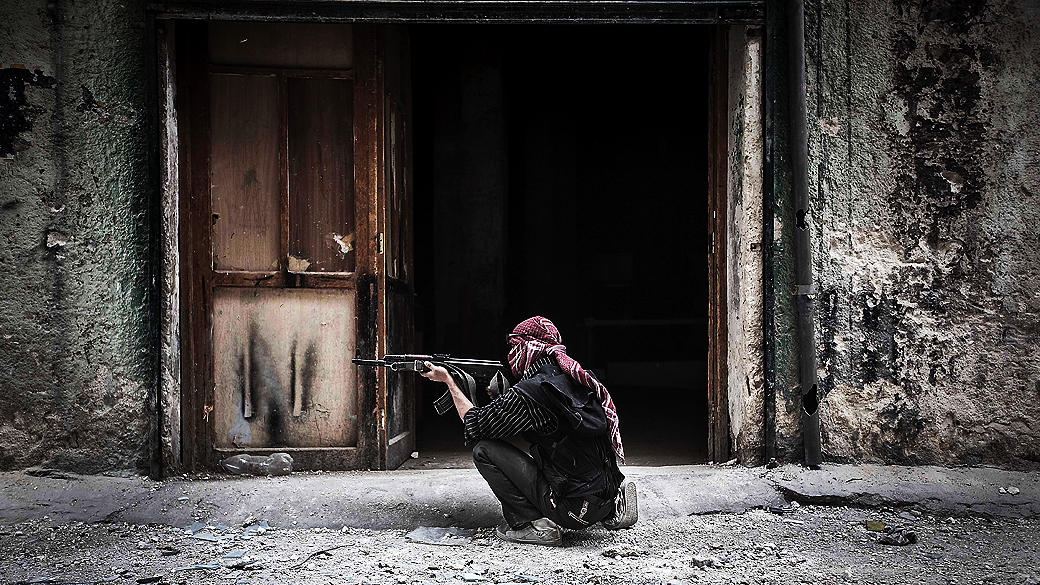 Membro do Exército Livre da Síria dispara contra inimigos na linha de frente de Moaskar, um dos campos de batalha no bairro de Karmal Jabl, em Aleppo
