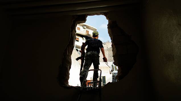 Rebelde é fotografado saido por buraco na parede, na Síria