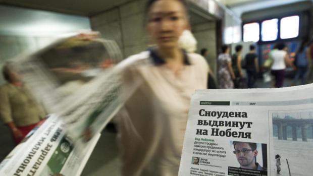 Em uma passagem subterrânea no centro de Moscou, mulher distribui jornal com a foto do ex-técnico da CIA Edward Snowden na capa