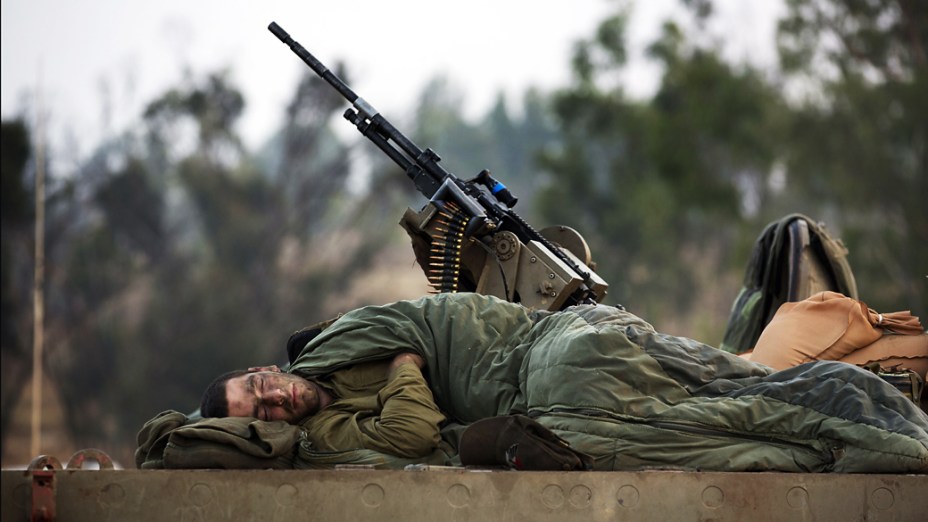Soldado israelense dorme sobre um tanque-de-guerra próximo a fronteira com a Faixa de Gaza