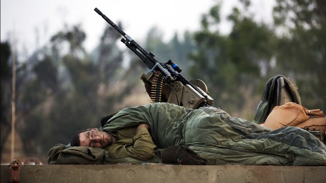 Soldado israelense dorme sobre um tanque-de-guerra próximo a fronteira com a Faixa de Gaza