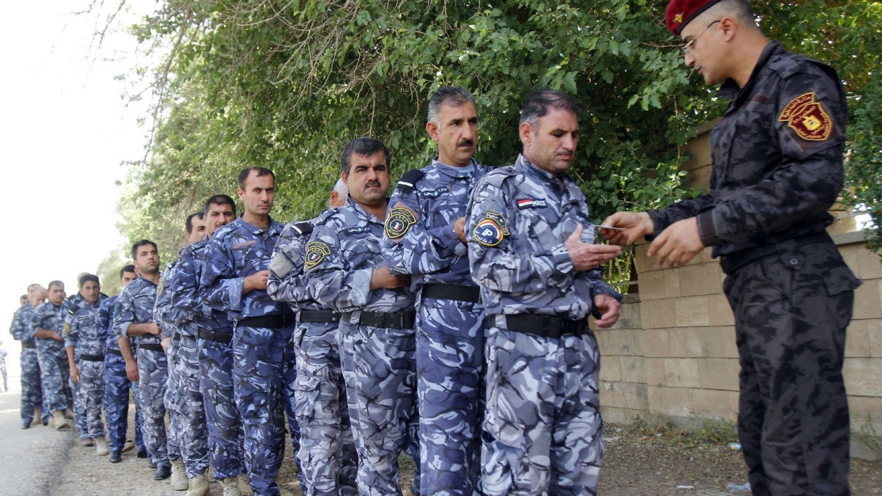 Soldados iraquianos fazem fila em frente a um colégio eleitoral em Kirkuk