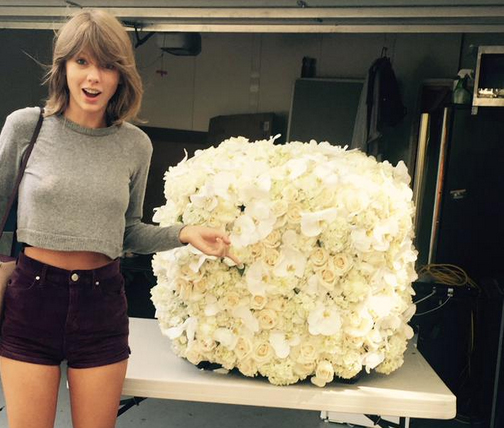 Taylor Swift ao lado do arranjo de flores enviados por Kanye West: novos melhores amigos