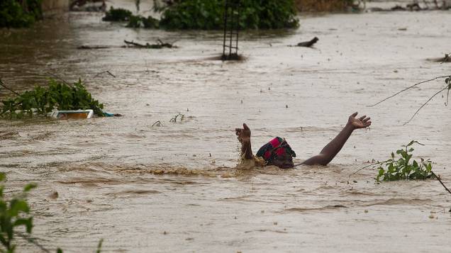 Mulher nada em área inundada pelas chuvas da tempestade tropical Isaac em Porto Príncipe, no Haiti
