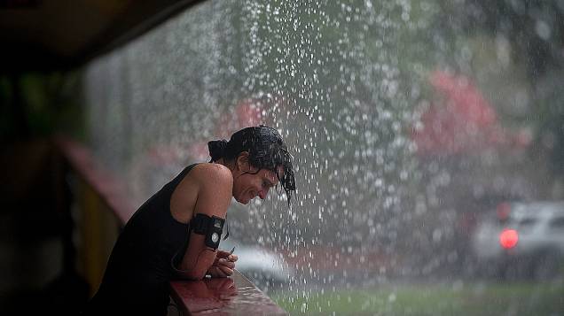 Nos Estados Unidos, mulher se refresca na chuva com a aproximação do furacão Isaac